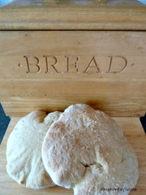 A bread bin with two stotties bedside it.