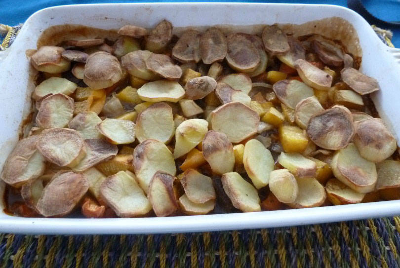 Panaculty, a dish of left over meats stock and root vegetables topped with sliced potatoes in a casserole dish on a table mat