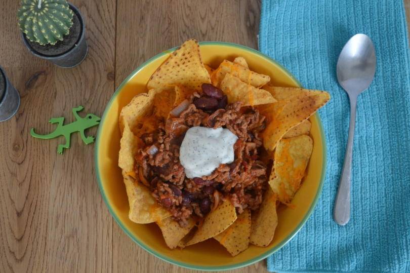 Simple beef nachos on a plate with sour cream on top