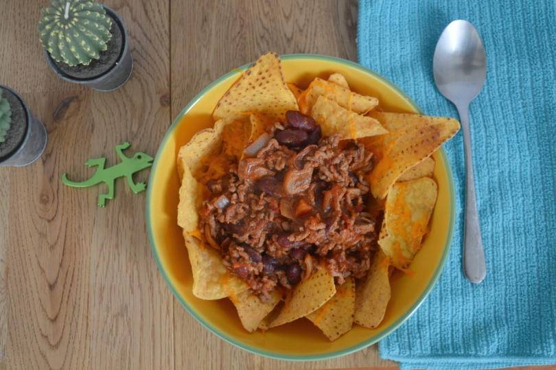 beef topping tortilla chips in a bowl on a table