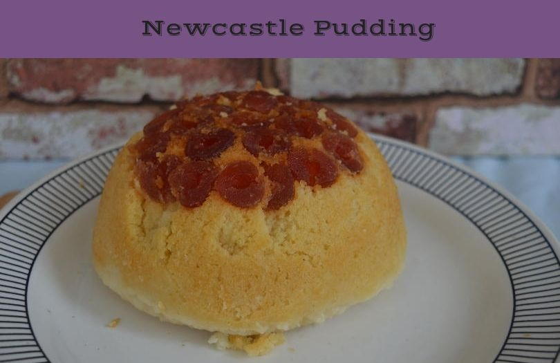 Newcastle pudding - a steamed pudding with a topping of cherries on a plate