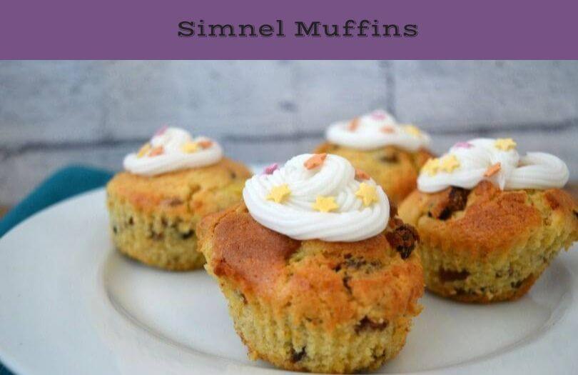 Simnel muffins on a plate. They have white icing decorated with stars.