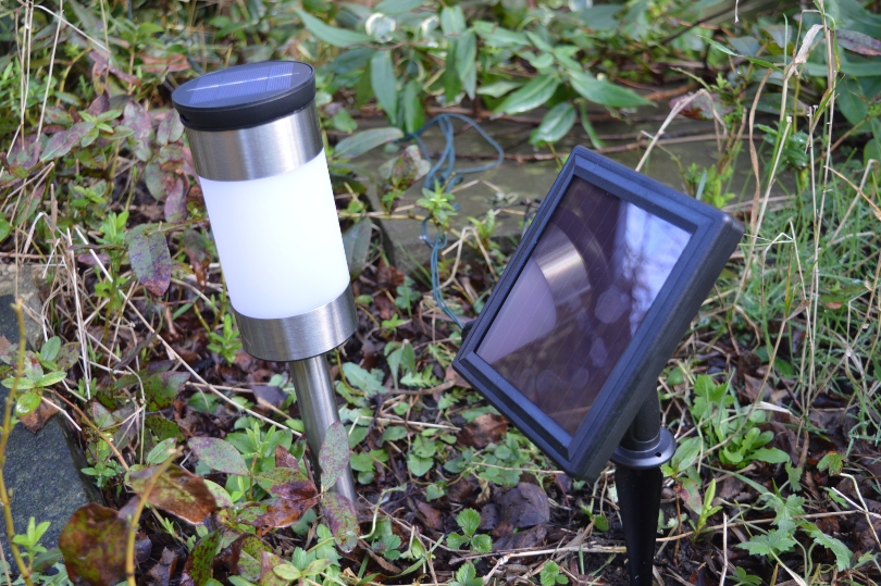 The solar panel for a outdoor solar lights in the garden next to a stake solar light