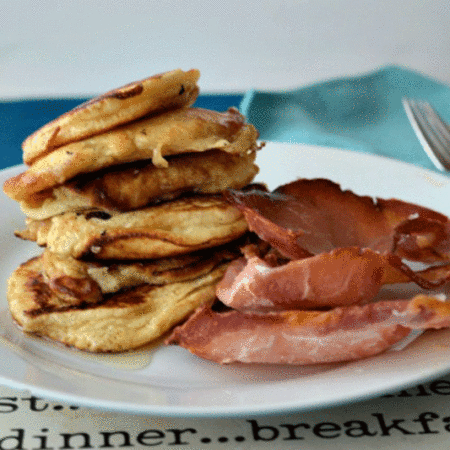 A stack of American pancakes on a plate with maple baked bacon
