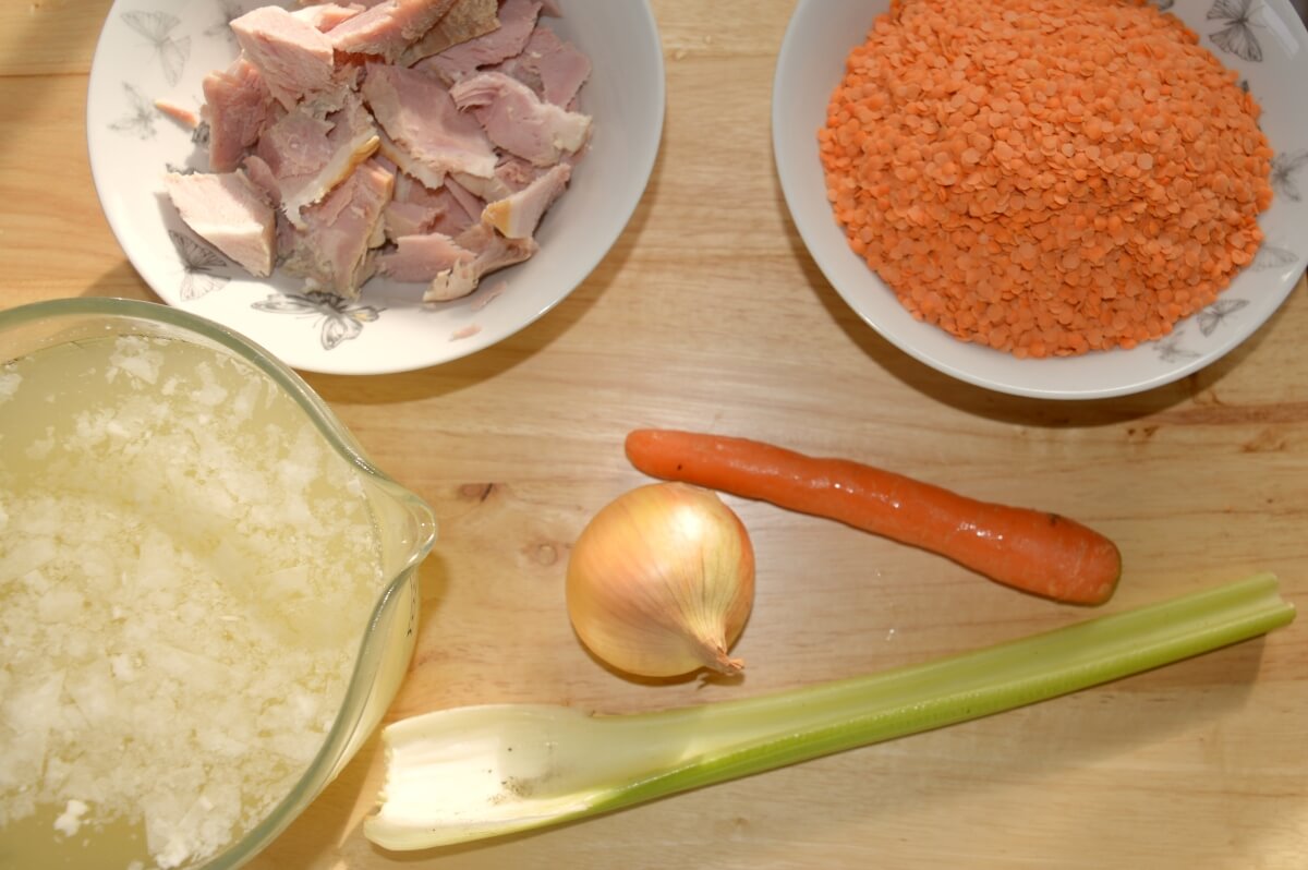 Ingredients for ham and lentil soup including red lentils, ham, vegetables and stock