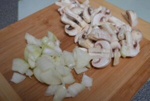 chopped onions and mushrooms on a chopping board