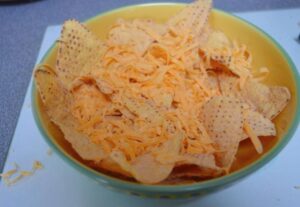 Tortilla chips in a bowl with cheese grated on top