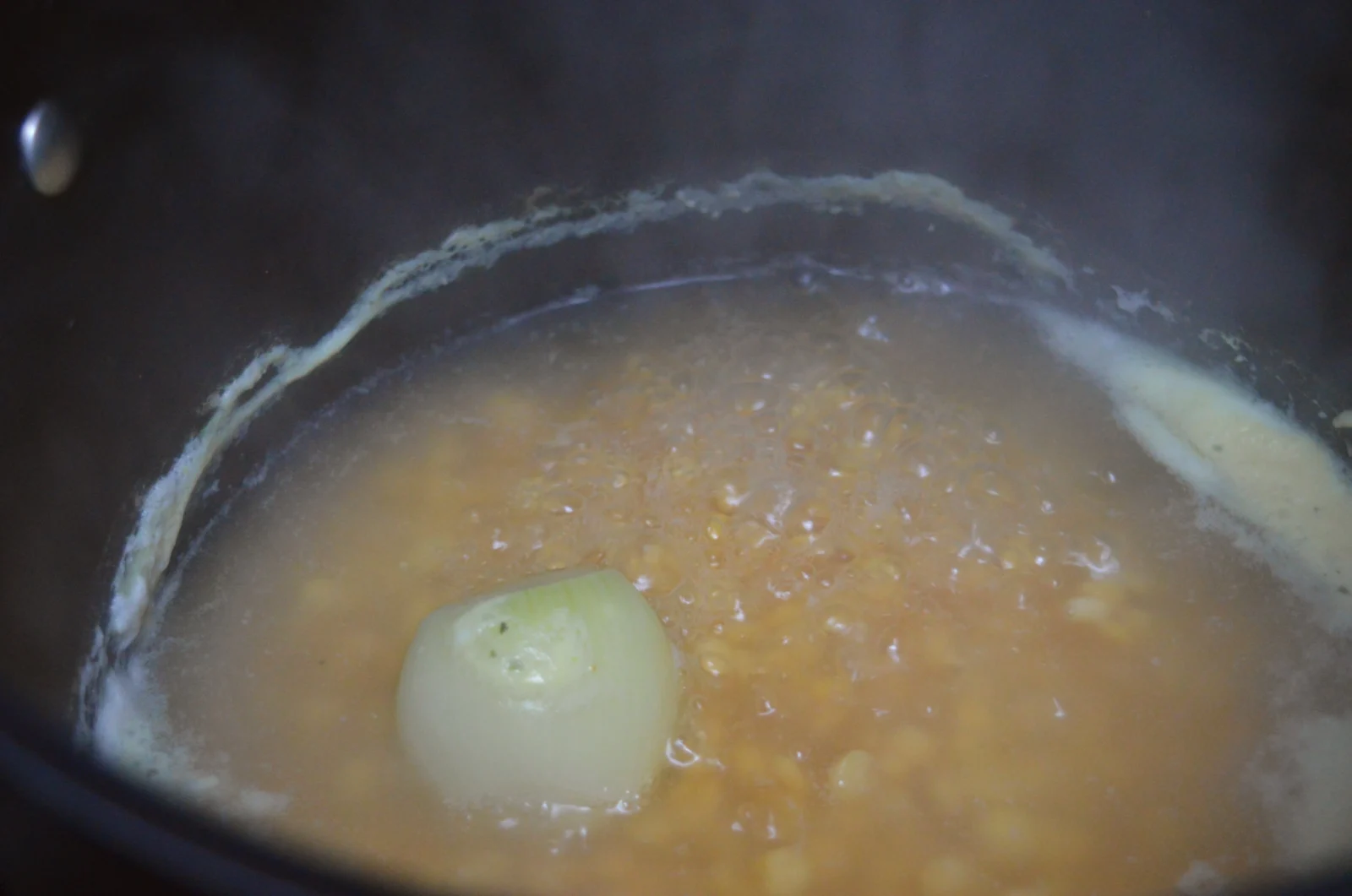 split peas simmering in a pan with an onion and stock