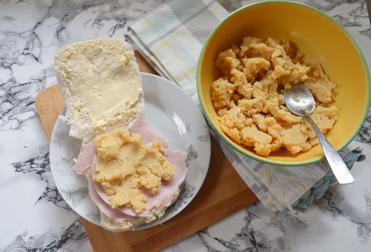 Pease pudding being spread on a ham stottie sandwich