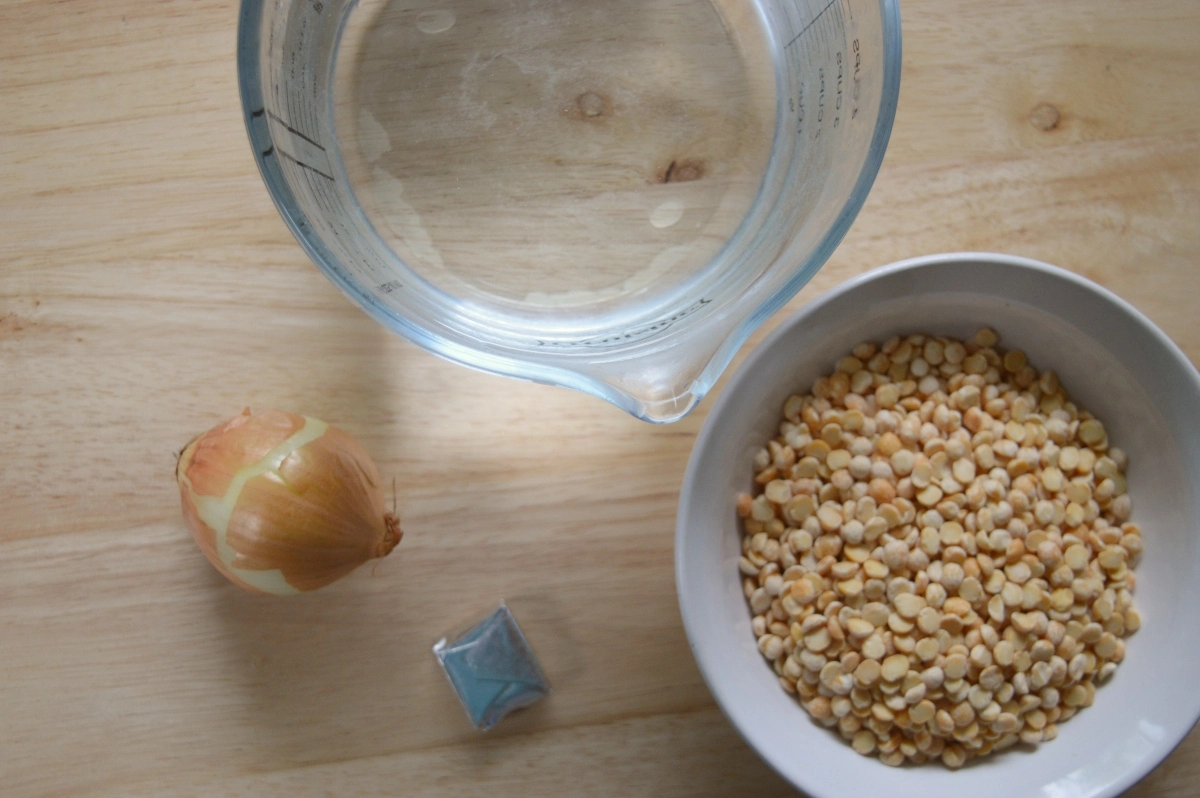 Ingredients for pease pudding on a table, yellow split peas, water, onion and a stock cube