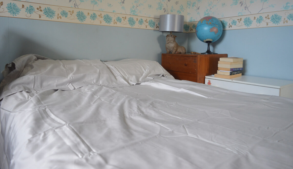 A double bed with grey cotton sheets