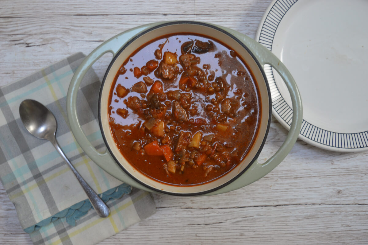 A casserole dish containing lamb and lentil stew on a table