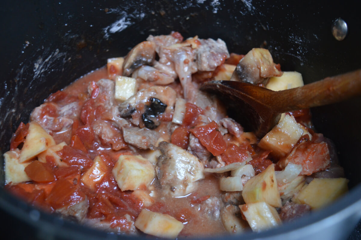 lamb and casserole vegetables in a pan with flour, tomatoes and stock