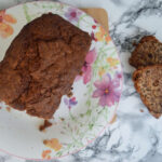 Banana and walnut bread. Two slices cut off beside the loaf on a flowery plate