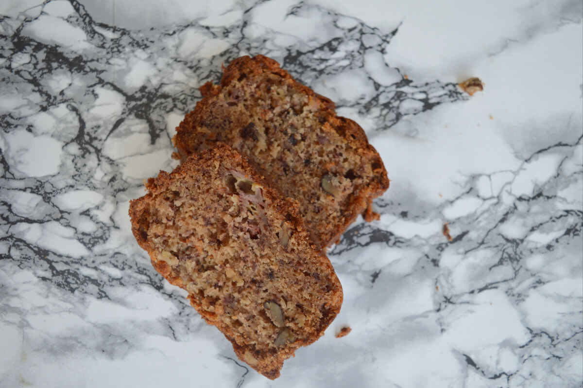 Two slices of walnut and banana bread on a marble counter