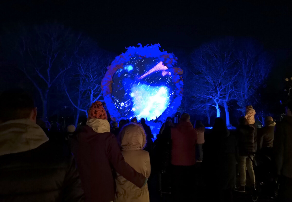 People standing watching a glowing portal full of stars