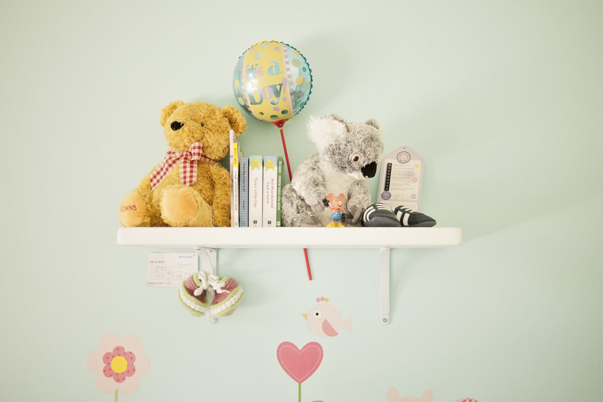 Soft toys and books on nursery shelf