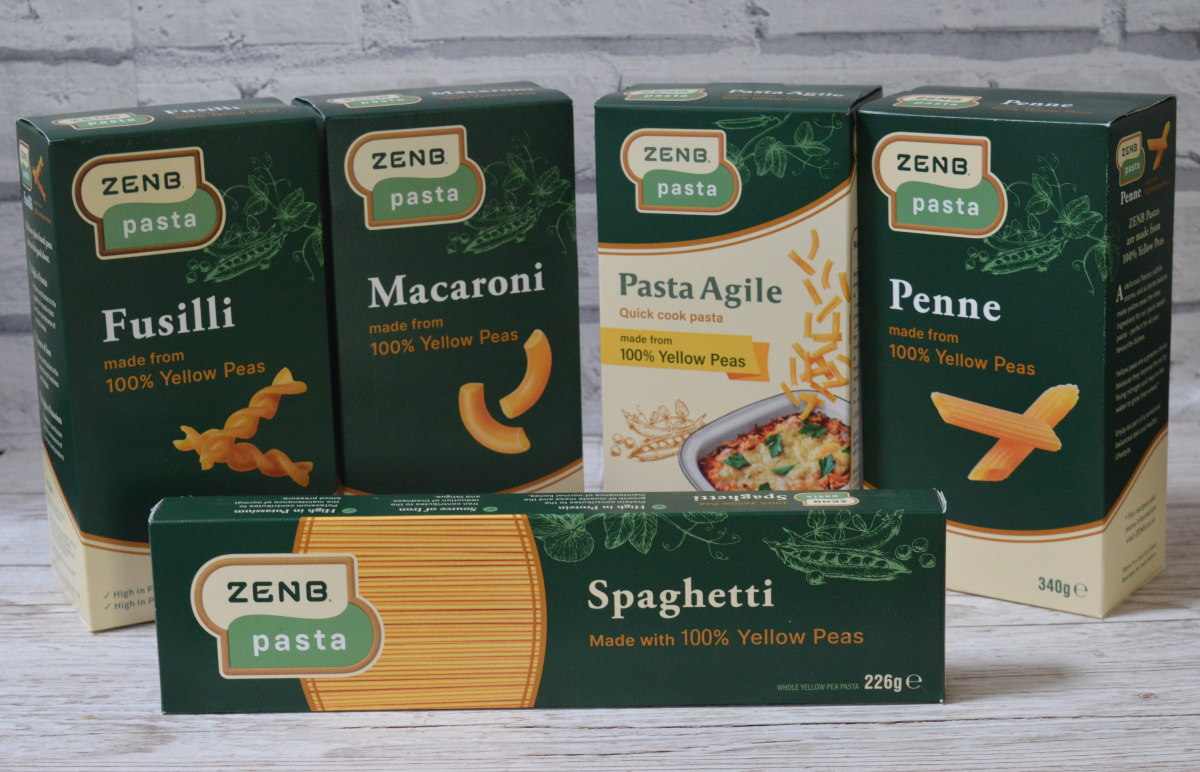 The full ZenB pasta range in front of grey bricks. There is a box of fusilli marcaroni, pasta agile, penne and spaghetti