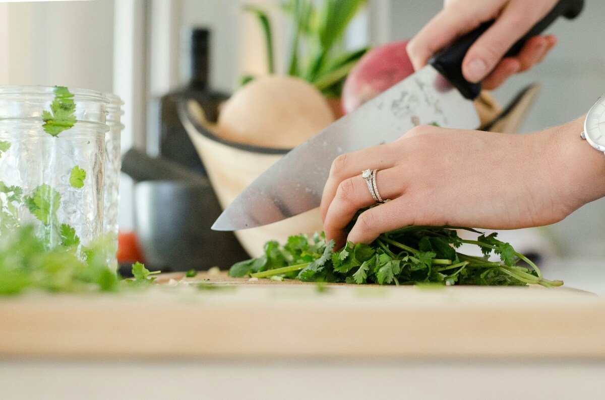 Ladies hands holding a knife chopping herbs