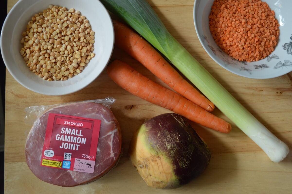 Ingredients laid out for making ham broth, including gammon, split peas, lentils, carrots, swede and leek.