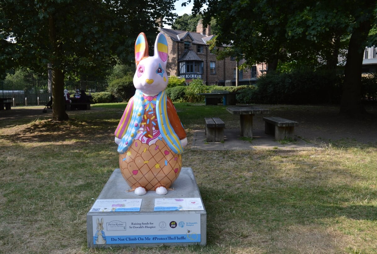 Gelato Peter Rabbit sculpture in Jesmond Dene surrounded by trees and picnic tables
