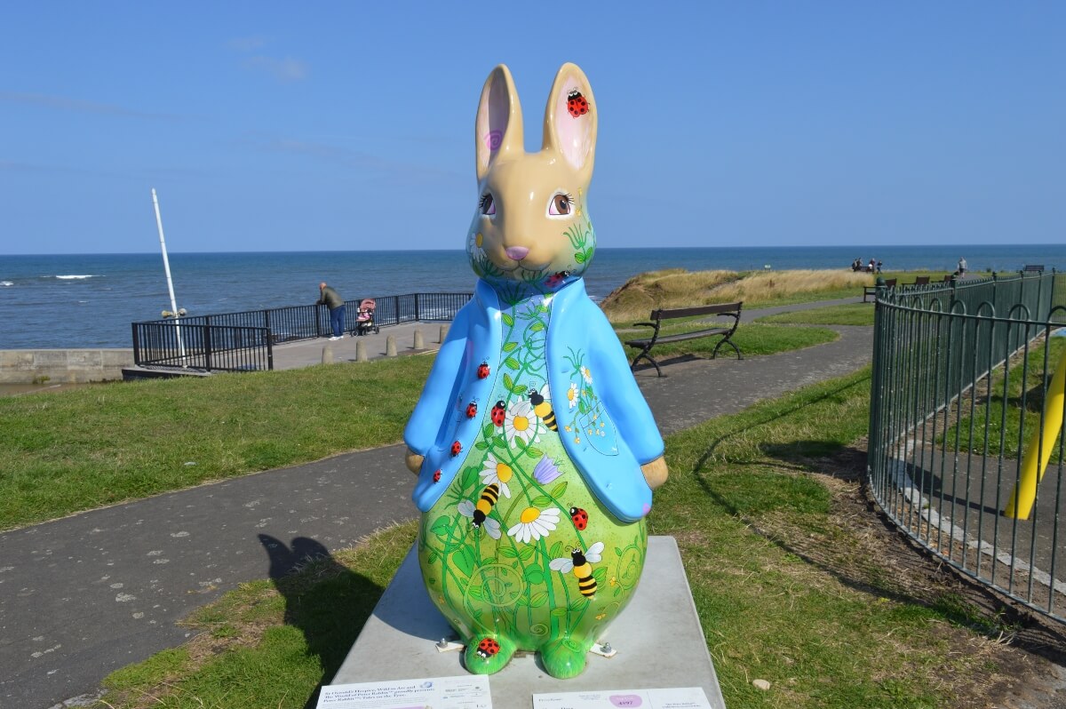 Hoppy Days Peter Rabbit sculpture with bees and wildflowers on Cullercoats seafront