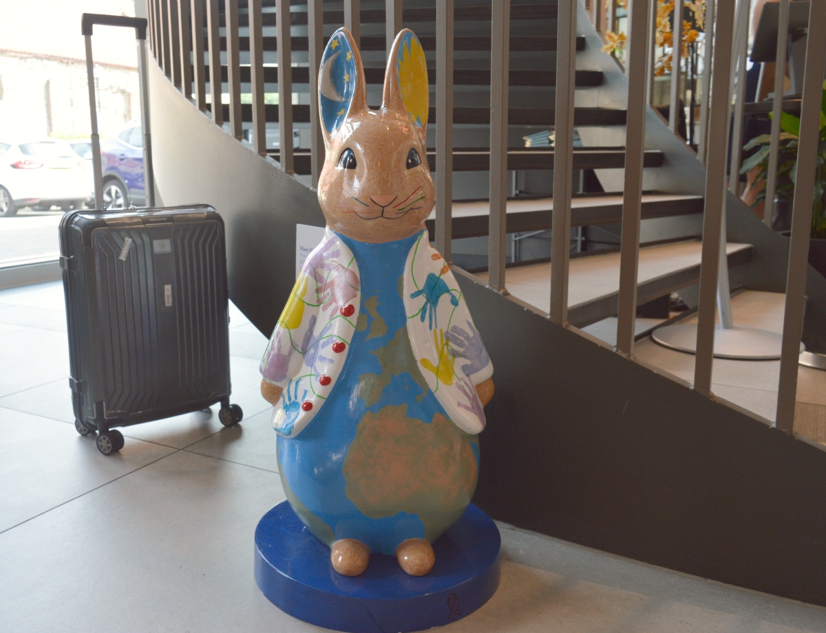 Many Hands, One World Peter Rabbit with a globe and handprints