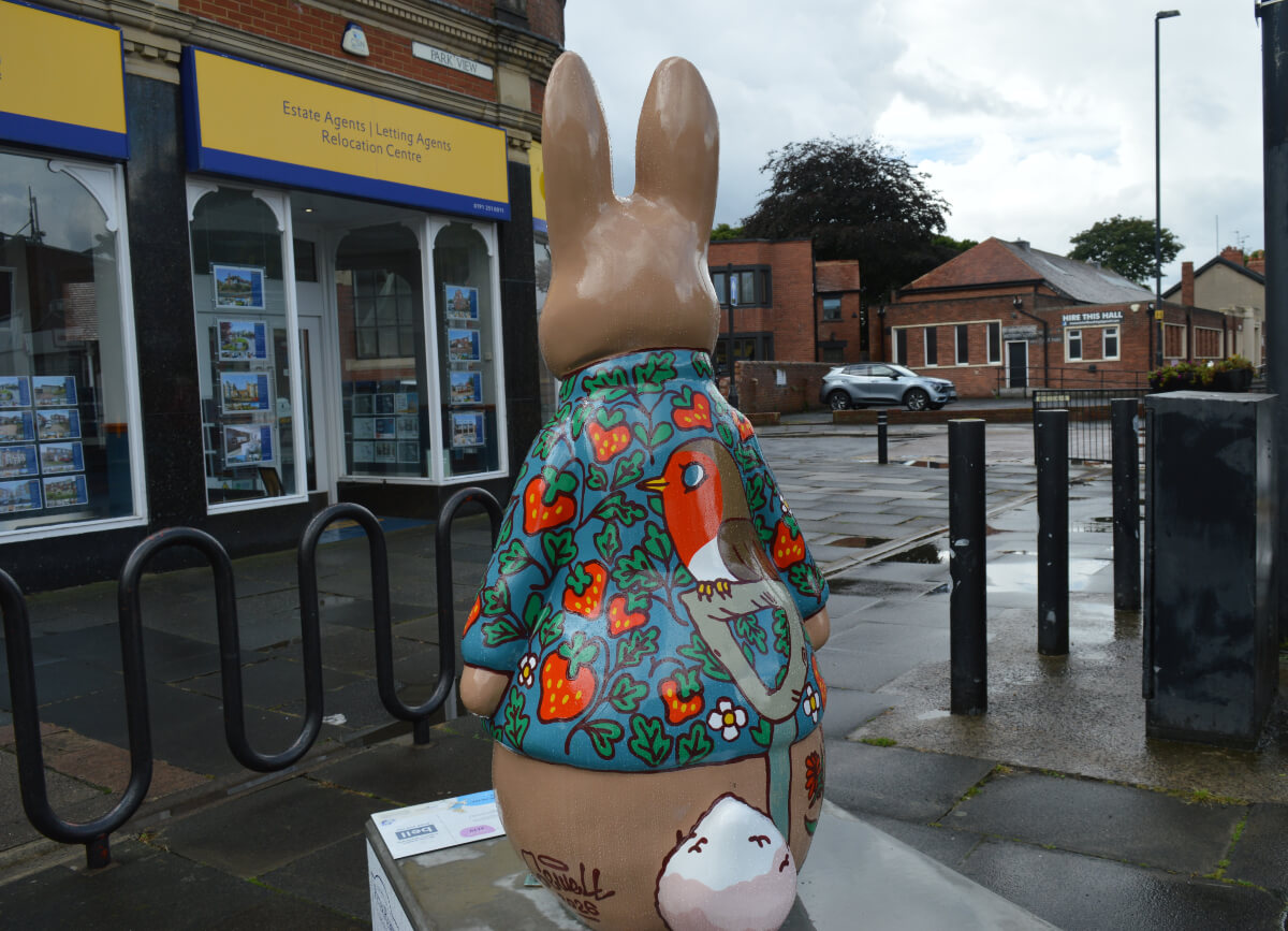 Back of Peter & The Robin sculpture showing a robin perched on a garden spade among strawberries